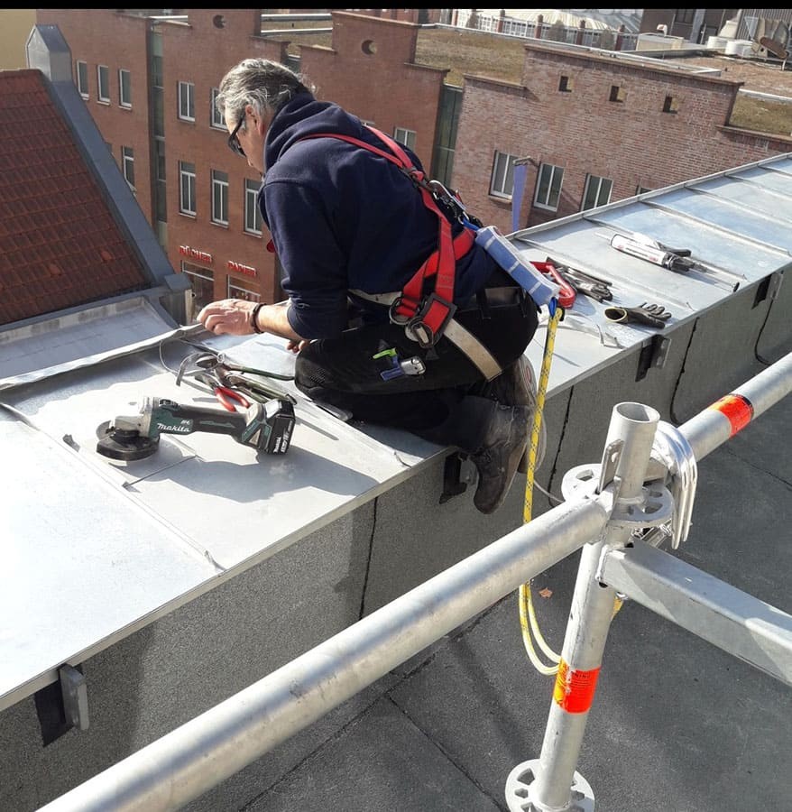 Dachdecker mit Auffanggurt an der Dachkante