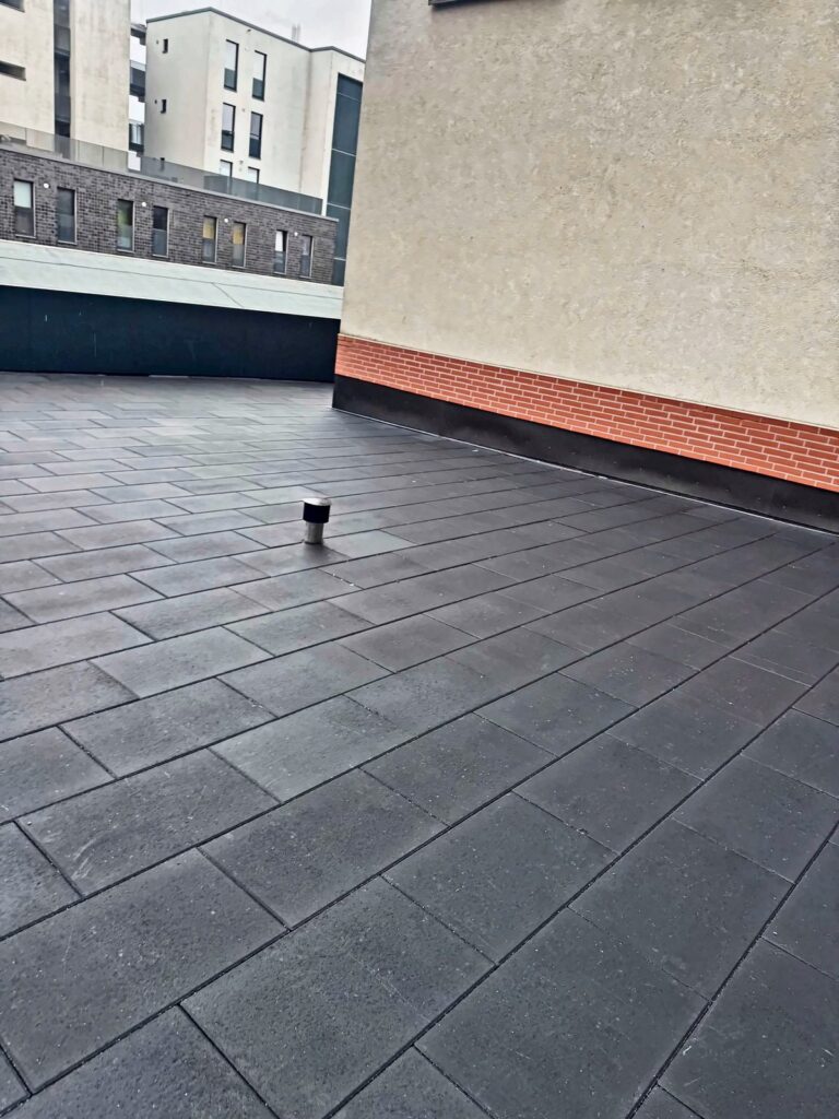 Fertige Dachterrasse mit großen grauen Platten vor einer hellen Hauswand, Hamburg