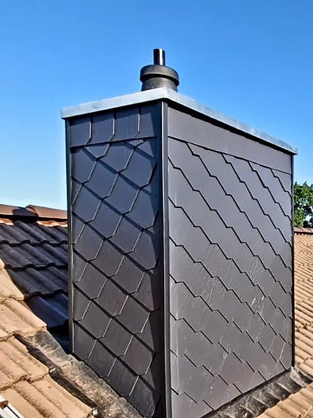 Schornstein mit neuer Schieferverkleidung vor blauem Himmel, Bad Segeberg